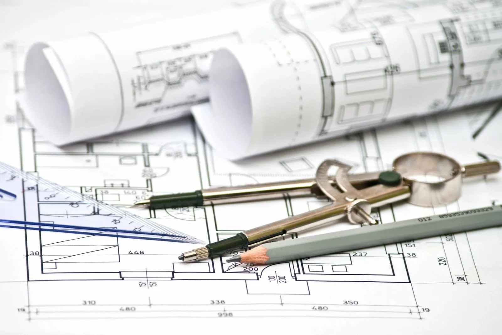 Drafting instruments and a compass resting on a set of building plans