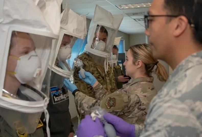 Airmen fit testing respirators and protective hoods during a training session